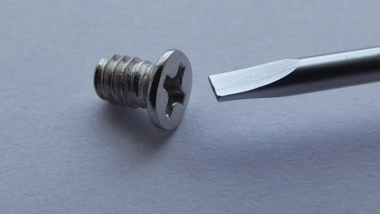 Un tournevis plat face à une vis cruciforme